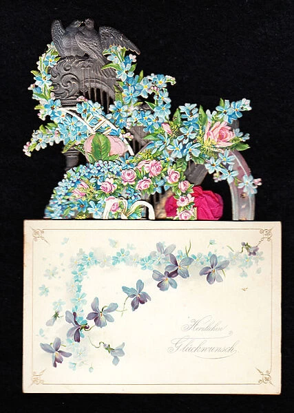 A Victorian die cut pop up greeting card of a harp entwined with forget-me-nots and roses