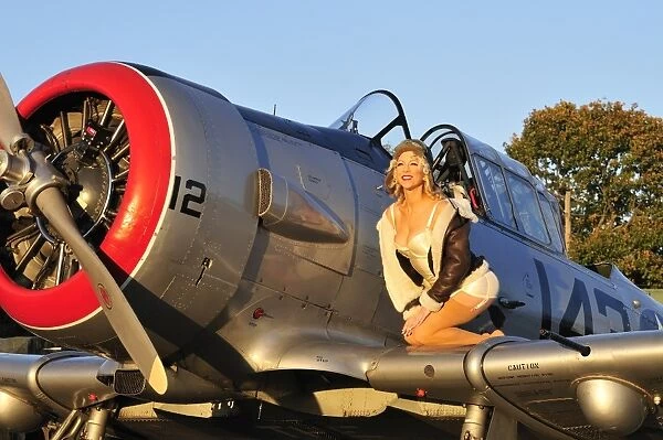 1940s style aviator pin-up girl posing with a vintage T-6 Texan aircraft