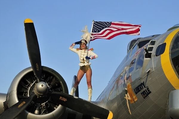1940s style majorette pin-up girl on a B-17 bomber with an American flag