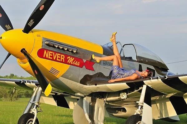 1940s style pin-up girl lying on the wing of a P-51 Mustang