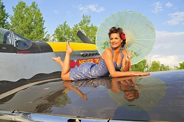 1940s style pin-up girl with parasol on a vintage P-51 Mustang