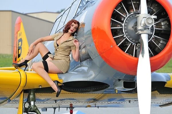 1940s style pin-up girl posing on a T-6 Texan training aircraft