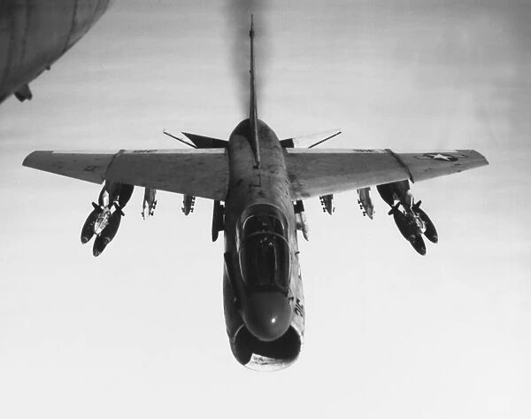 An A-7 Corsair II flies toward targets in Vietnam, armed with bomb clusters, 1969
