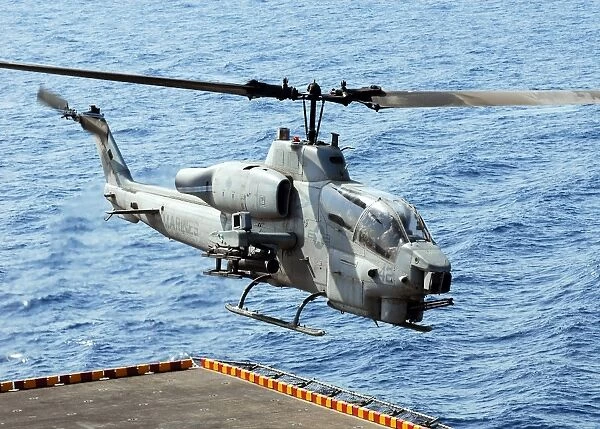 An AH-1W Super Cobra helicopter launches off the flight deck of USS Peleliu