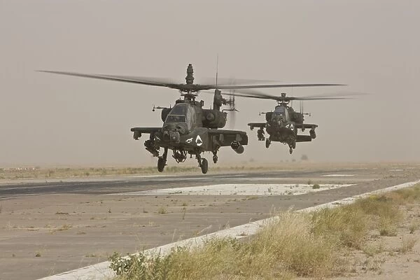 Two AH-64 Apache helicopters prepare to land on on the runway