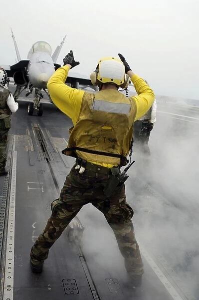 An aircraft director signals a F  /  A-18C Hornet on the flight deck of USS Kitty Hawk