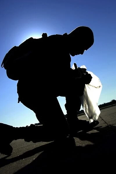 An Airman performs a foreign object disposal walk on the flight line