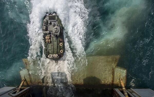 An amphibious assault vehicle exits the well deck of USS Bataan