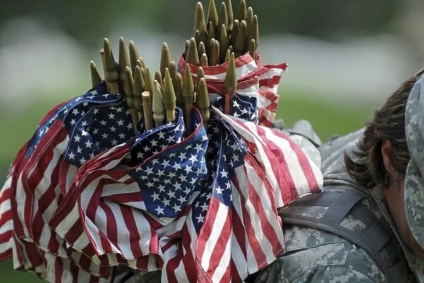 An Army soldiers backpack overflows with small American flags