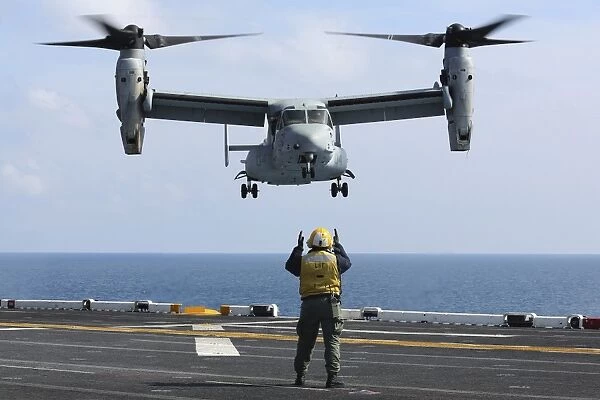 An aviation boatswains mate directs the landing of an MV-22 Osprey
