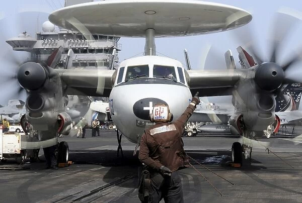 Aviation Electronics Technician directs an E-2C Hawkeye to start its engines