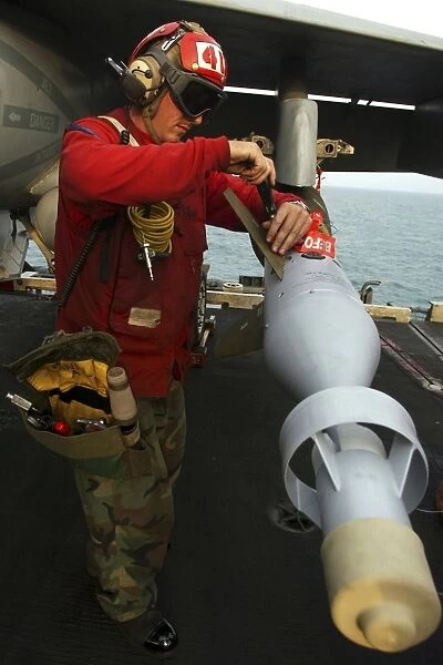 Aviation Ordnanceman attaches a stabilizer fin to a GBU-16 1000 pound laser-guided bomb