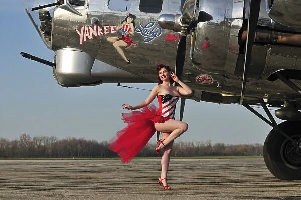 Beautiful 1940s style pin-up girl standing in front of a B-17 bomber