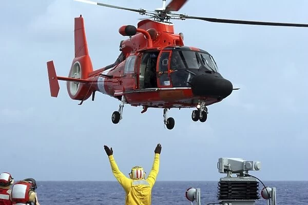 Boatswain Mate directs a HH-65A Dolphin aboard the guided-missile destroyer USS Russell