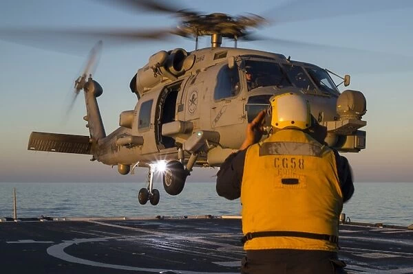 Boatswains Mate guides an MH-60R Sea Hawk onto the flight deck