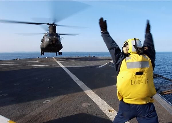 Boatswains Mate signals to a CH-47 Chinook helicopter