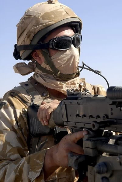 A British Army soldier mans a machine gun mounted on top of a land rover