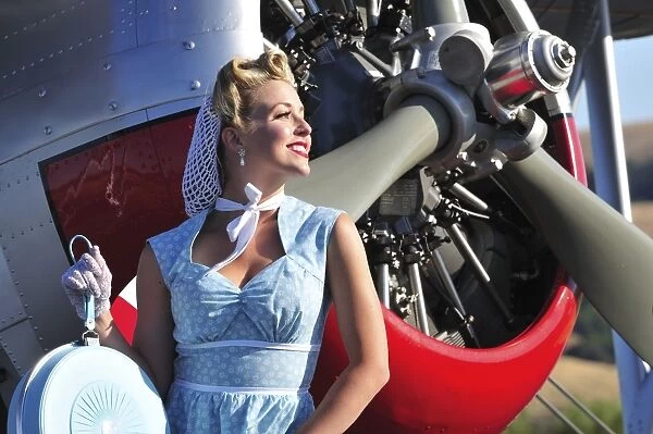 Close-up of a 1940s style pin-up girl in front of a vintage F3F biplane