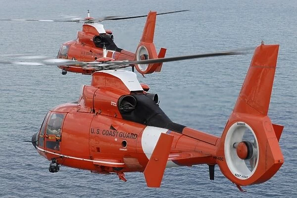 Two Coast Guard HH-65C Dolphin helicopters fly in formation over the Atlantic Ocean