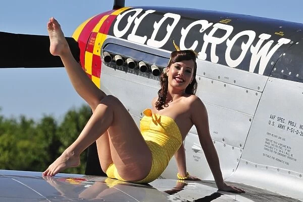 Cute pin-up girl sitting on the wing of a P-51 Mustang