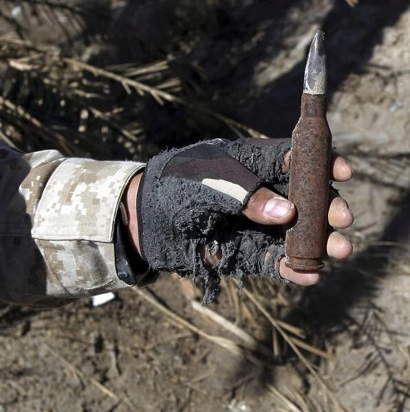 An engineer displays a bullet found near a weapons cache