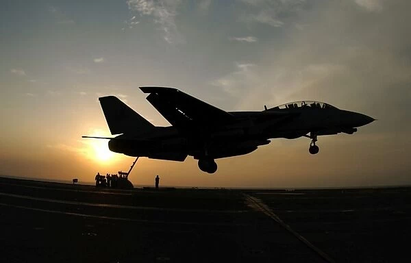 An F-14D Tomcat makes an arrested landing as the sun sets