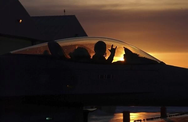 An F-16 Fighting Falcon Fighter Pilot gives the mission accomplished sign while taxiing