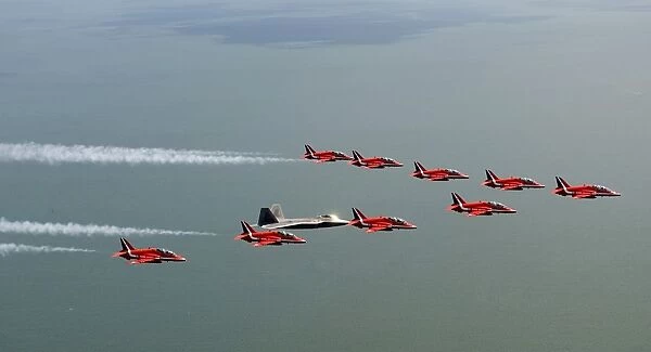 A F-22 Raptor flies in formation with the Royal Air Force Aerobatic Team, The Red Arrows