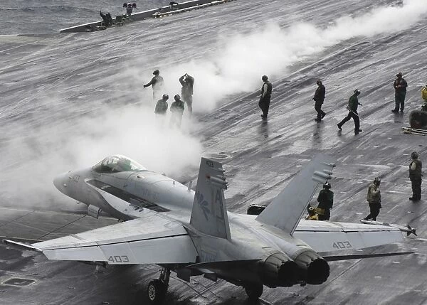 An F  /  A-18C Hornet taxies to a steam-powered catapult on the flight deck of USS Theodore