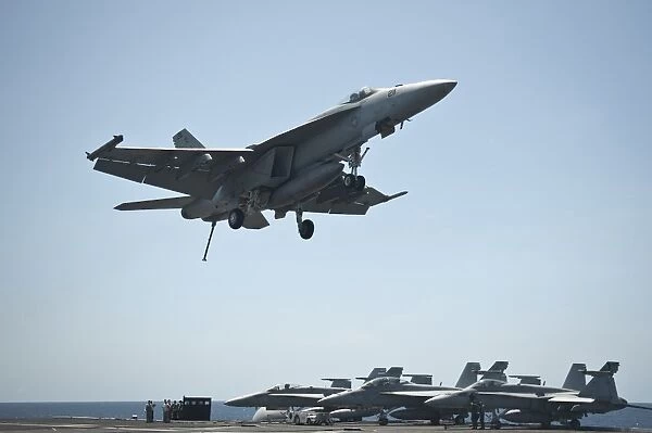 An F  /  A-18E Super Hornet flies over the flight deck of USS Nimitz