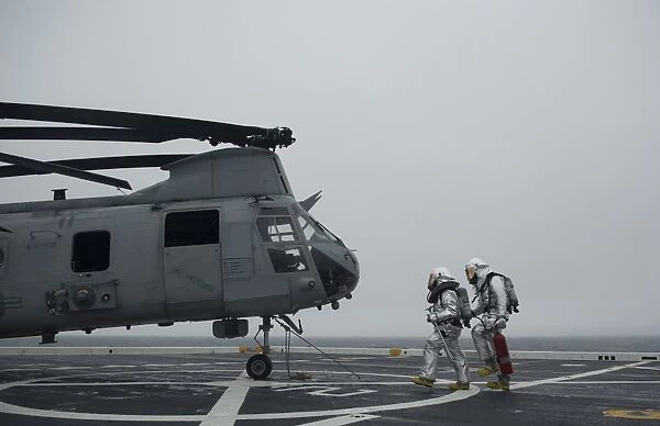 Firefighters approach a CH-46 Sea Knight to simulate a rescue