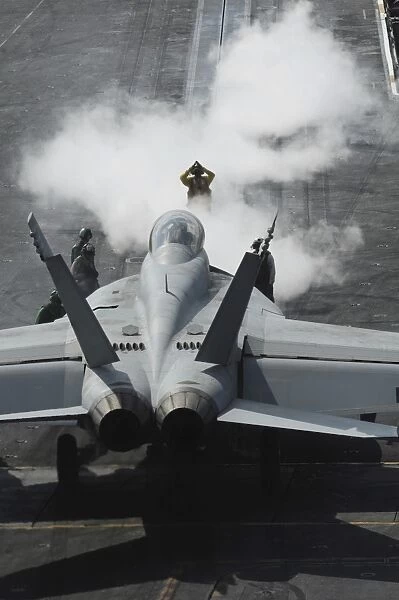 A flight deck director signals an F  /  A-18F Super Hornet onto catapult one aboard the