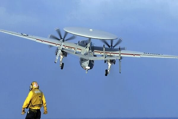A flight deck director watches an E-2C Hawkeye taking off