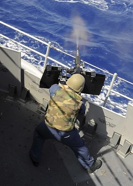 Gunners Mate firing a. 50 caliber machine gun aboard the guided-missile cruiser USS