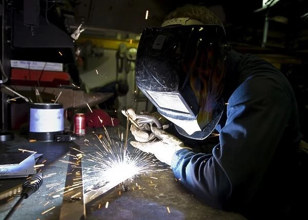 Hull Maintenance Technician strikes a welding rod