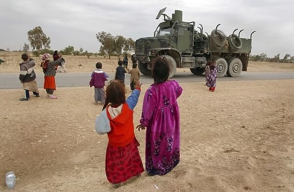 Iraqi children wave to an American convoy