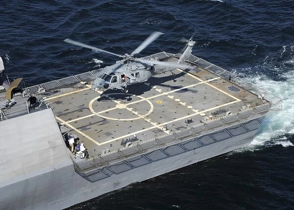 The littoral combat ship USS Freedom with an MH-60S Sea Hawk helicopter