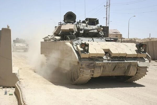 An M2 Bradley Fighting Vehicle patrols past Command Post Hit, Iraq