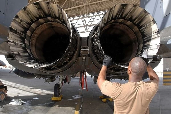 A maintainer inspects the engine of an F-15E Strike Eagle