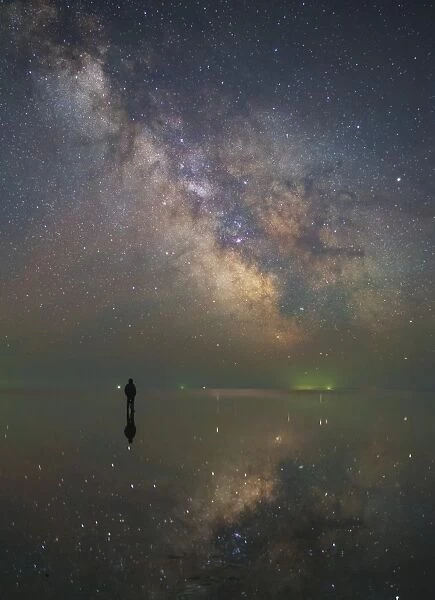 Man stands alone on Lake Elton in Russia under the center of the Milky Way
