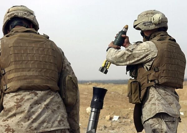 A Marine prepares to drop a high explosive round into a mortar tube
