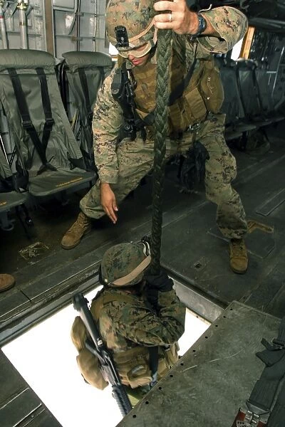 A Marine sends a fellow Marine down the hell hole of a CH-53E Super Stallion