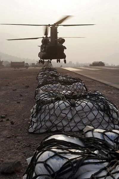 Marines attach sling loads to the body of an Army CH-47 Chinook cargo helicopter