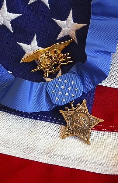 The Medal of Honor rests on a flag beside a SEAL trident