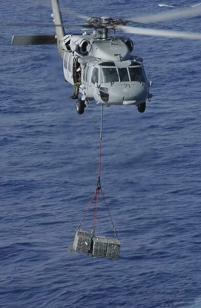 An MH-60S Knighthawk transports supplies during a replenishment at sea