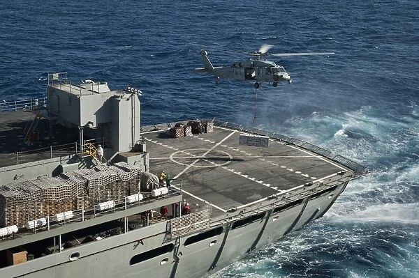 An MH-60S Sea Hawk conducts a vertical replenishment with USNS Rainier
