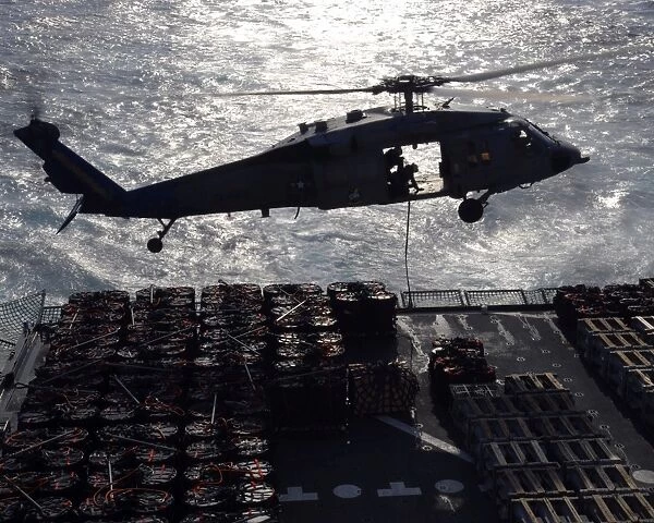 An MH-60S Seahawk helicopter conducts a vertical replenishment