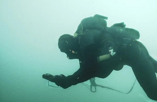 A Navy SEAL combat swimmer navigates the water utilizing a compass board