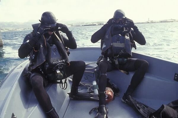 Navy SEALs combat swimmers in a utility boat adjust their dive masks