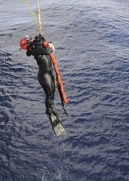 An Operations Specialist is lifted out of the ocean